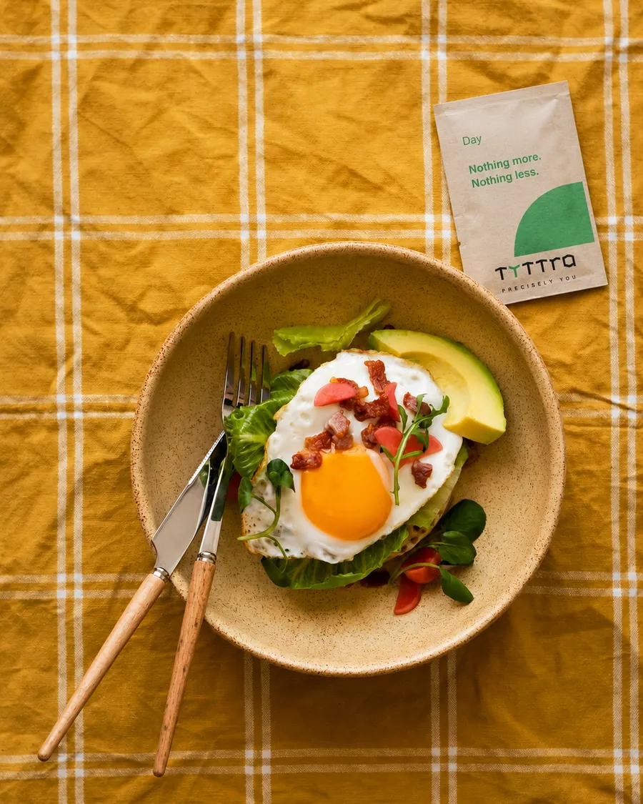 A breakfast of egg, avocado and greens with a Tyttra Day sachet on the table