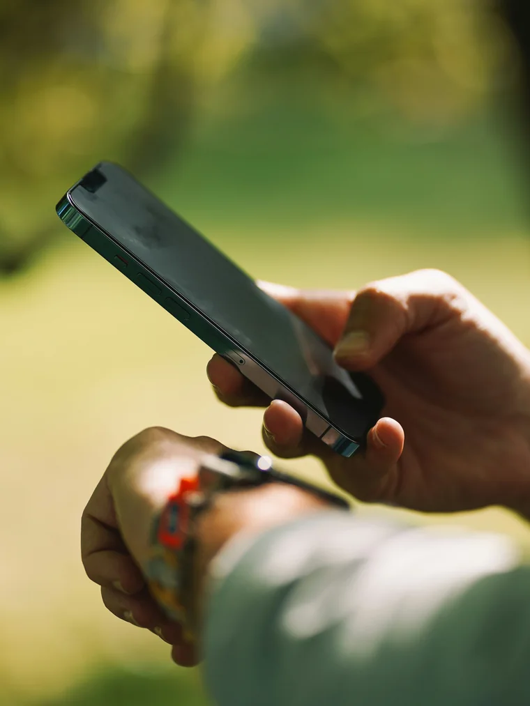Someone outdoors checking their protocol on their phone, wearable on wrist